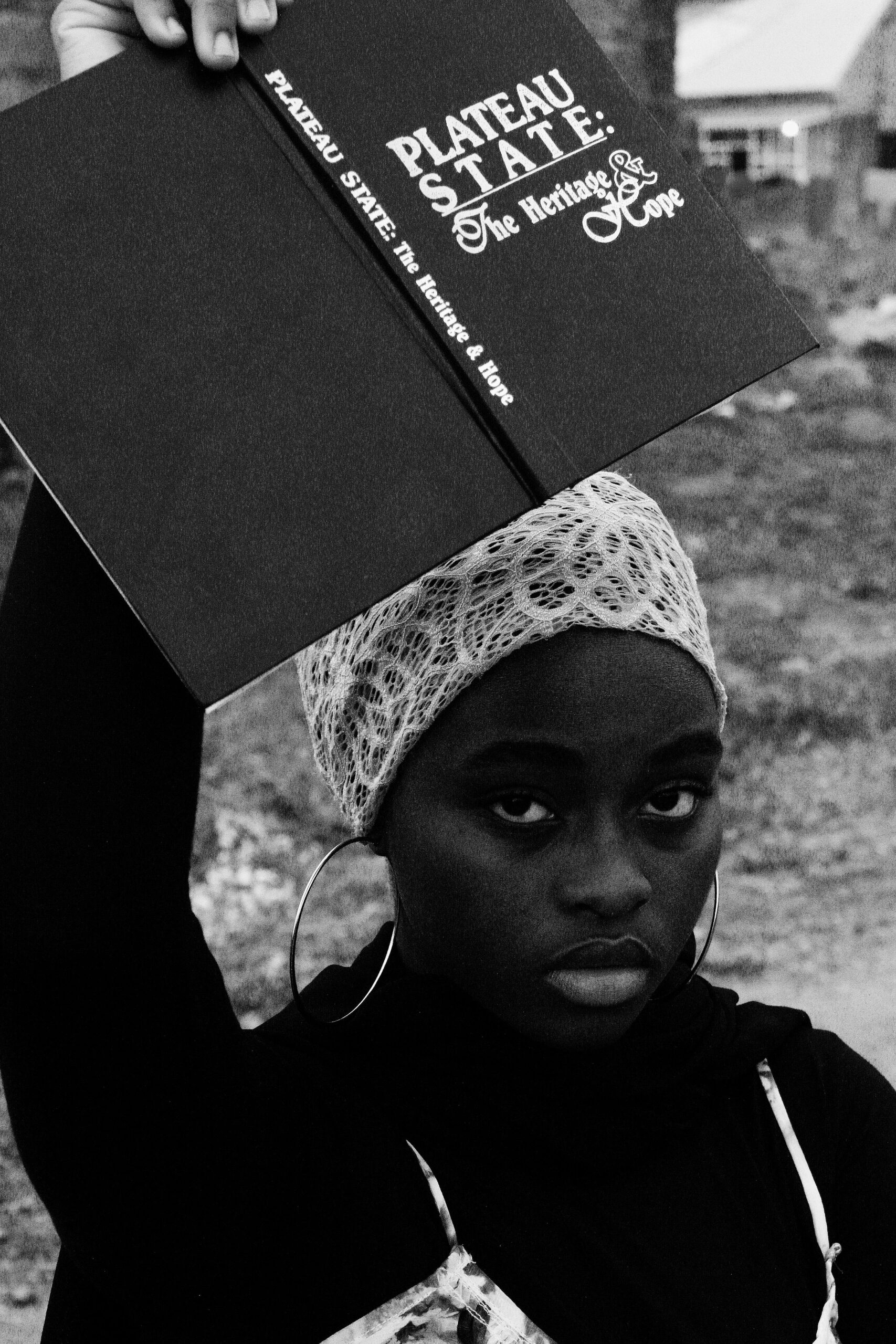 Home Black and white portrait of a teenager holding a book in Nigeria.